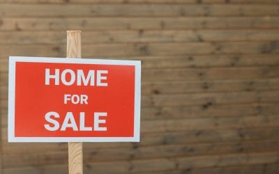 Close-up of a red home for sale sign against a wooden backdrop, ideal for real estate use.